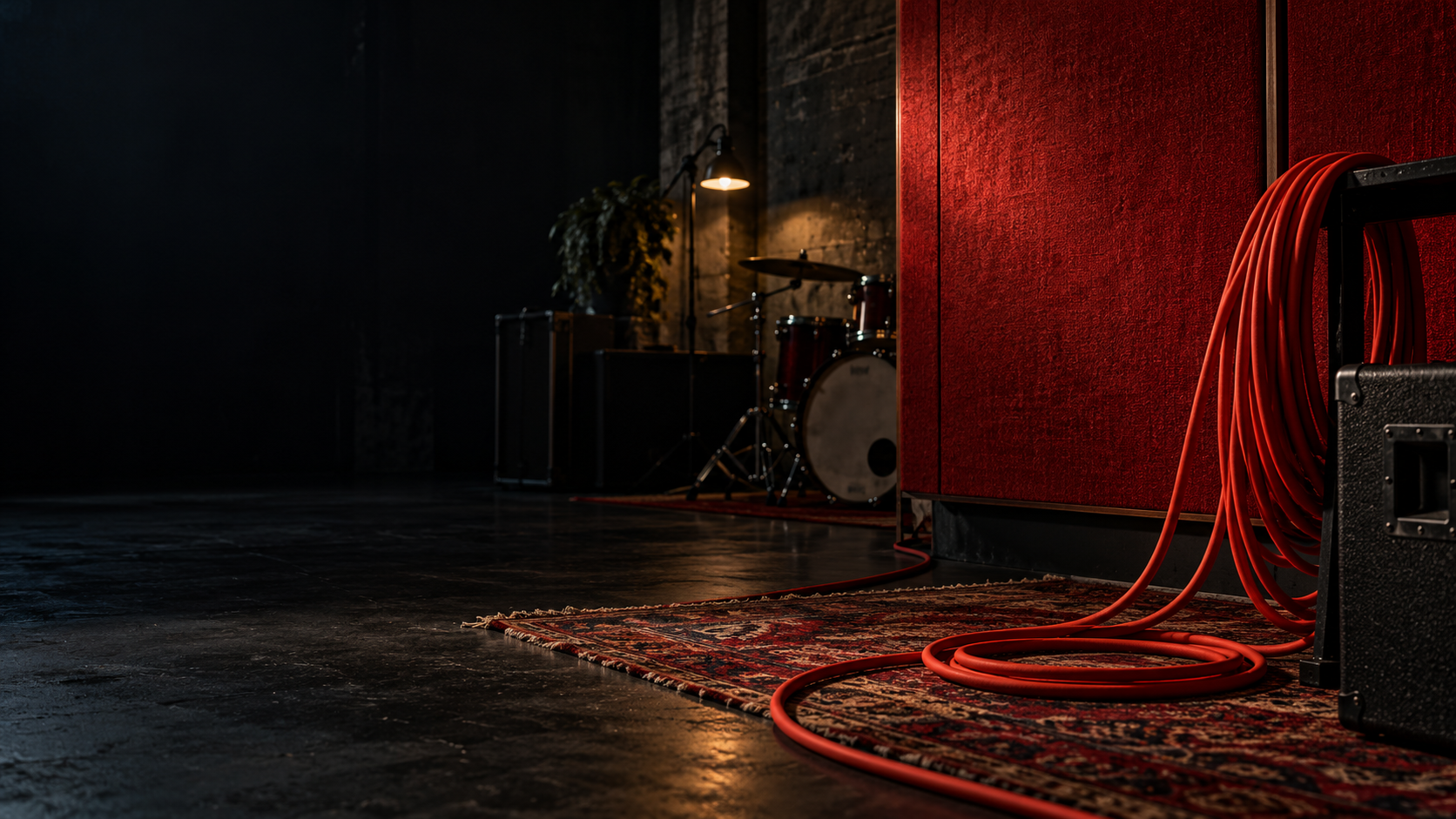 A dark music studio with red acoustic textures and a coiled audio cable